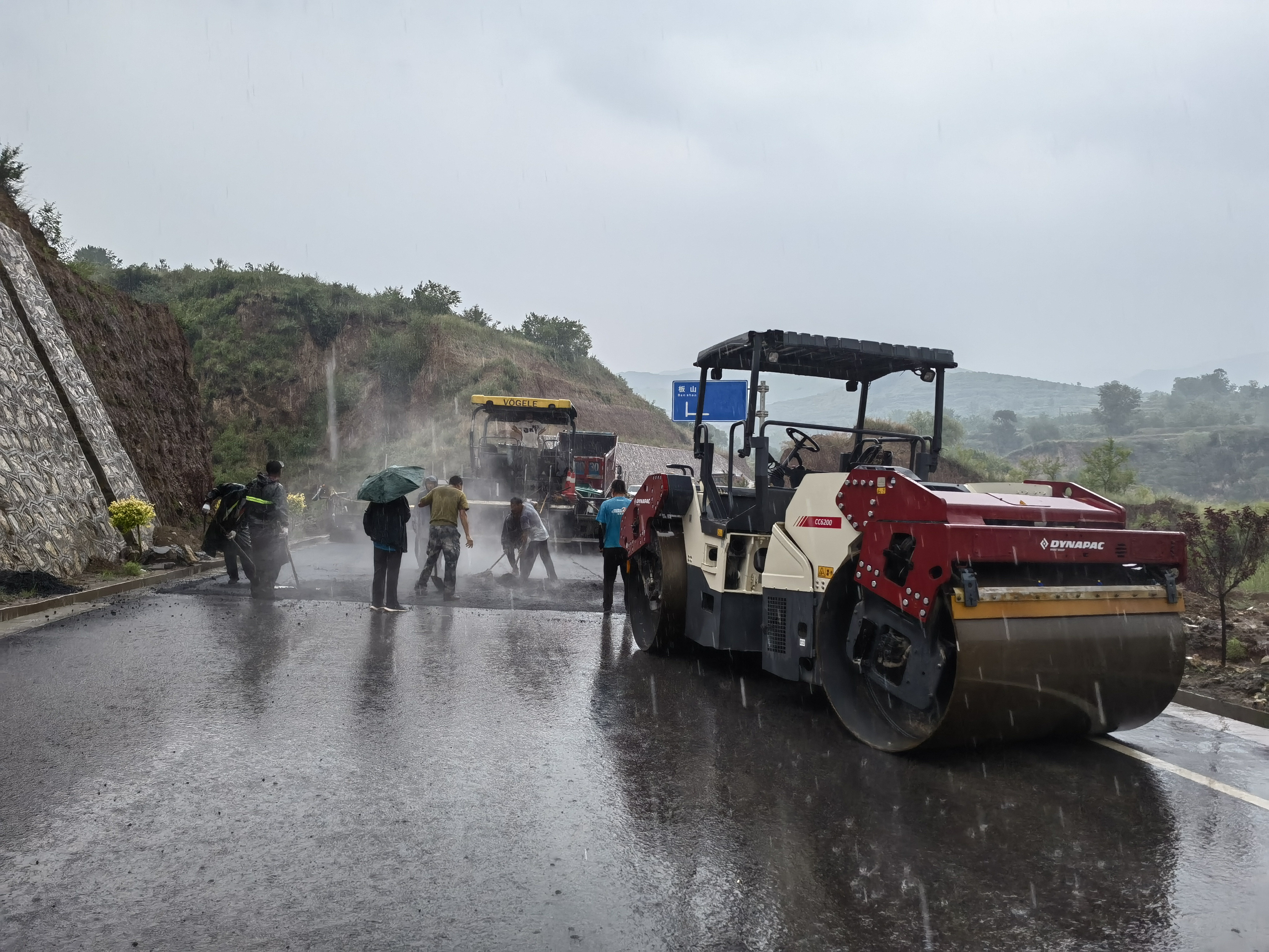 路桥工人在大雨中抢修道路。李华英 摄