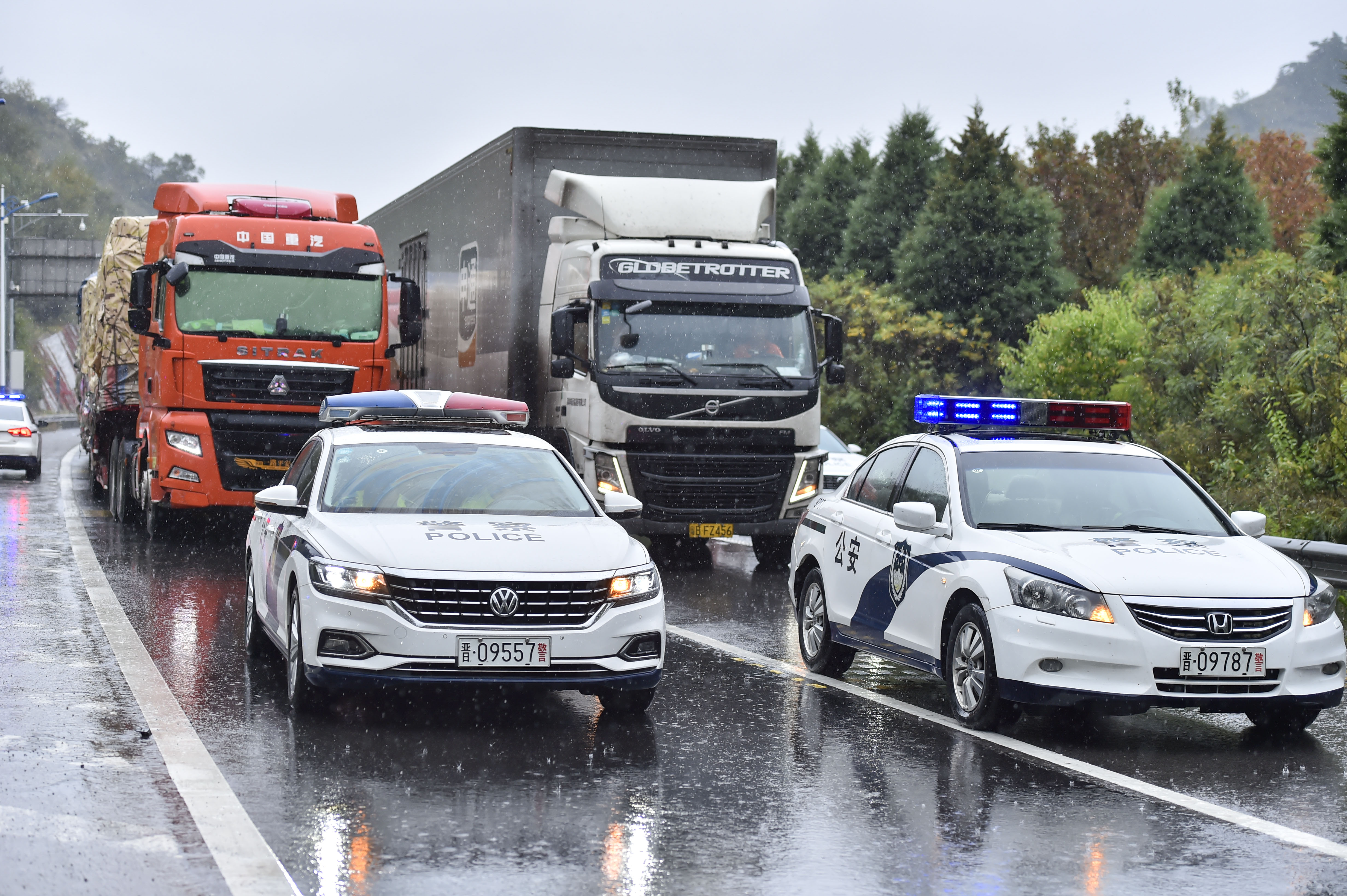 高速交警通过警车带道、压速通行保障降雨天气车辆安全行驶。