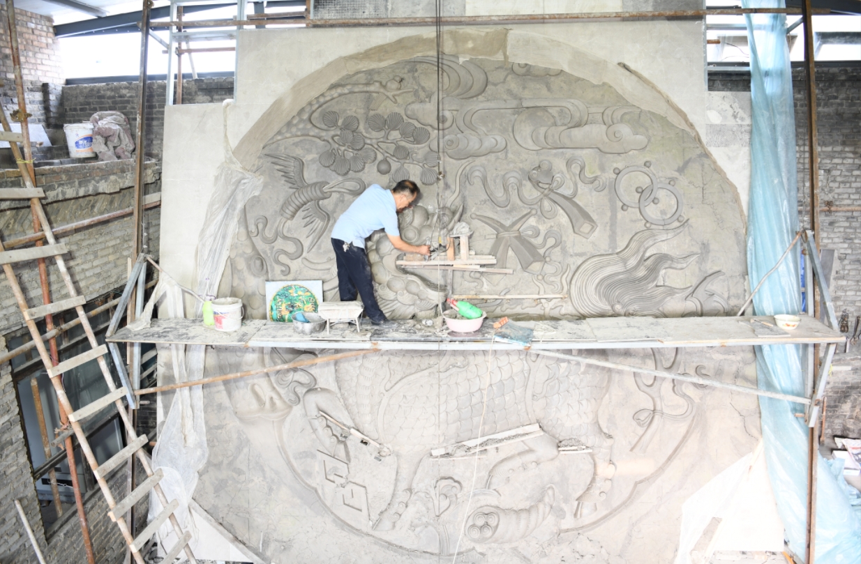 劉開寶正在為高6.18米的《麒麟獻瑞琉璃壁心》進行泥塑造型精修。（圖片由受訪者提供）