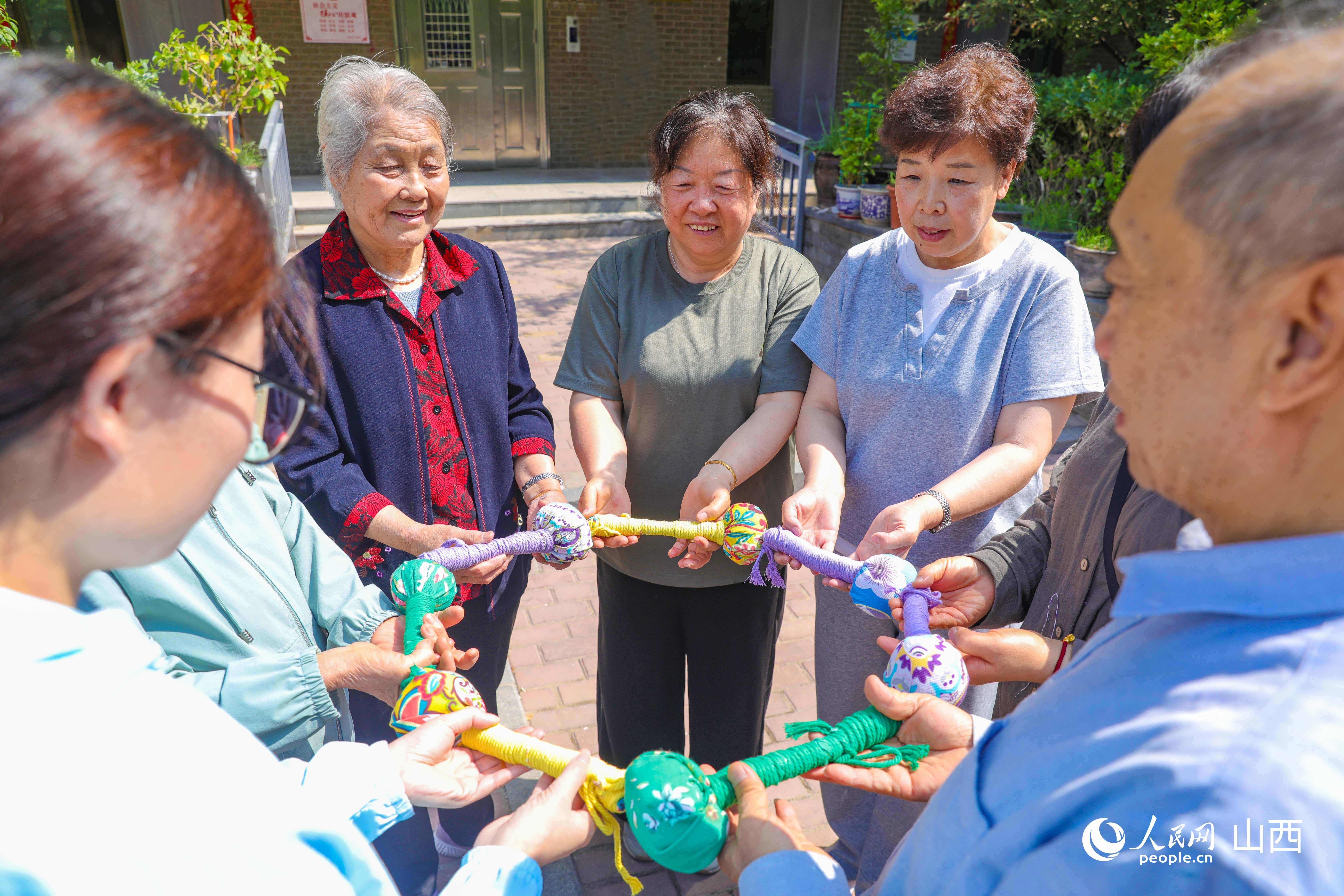 居民们展示五颜六色的棉麻拍打棒。