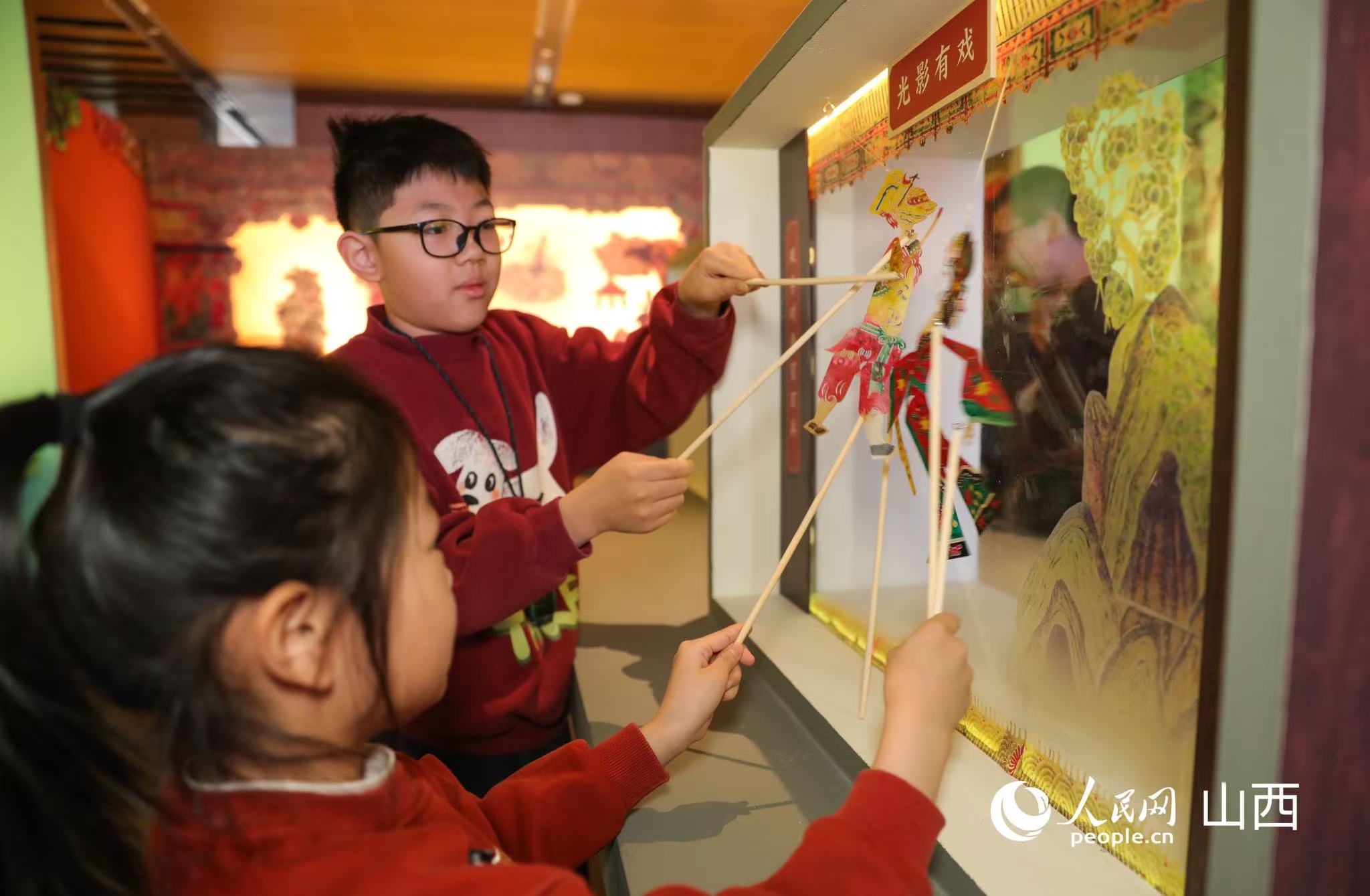 学生们亲手体验皮影表演。人民网记者 王帆摄