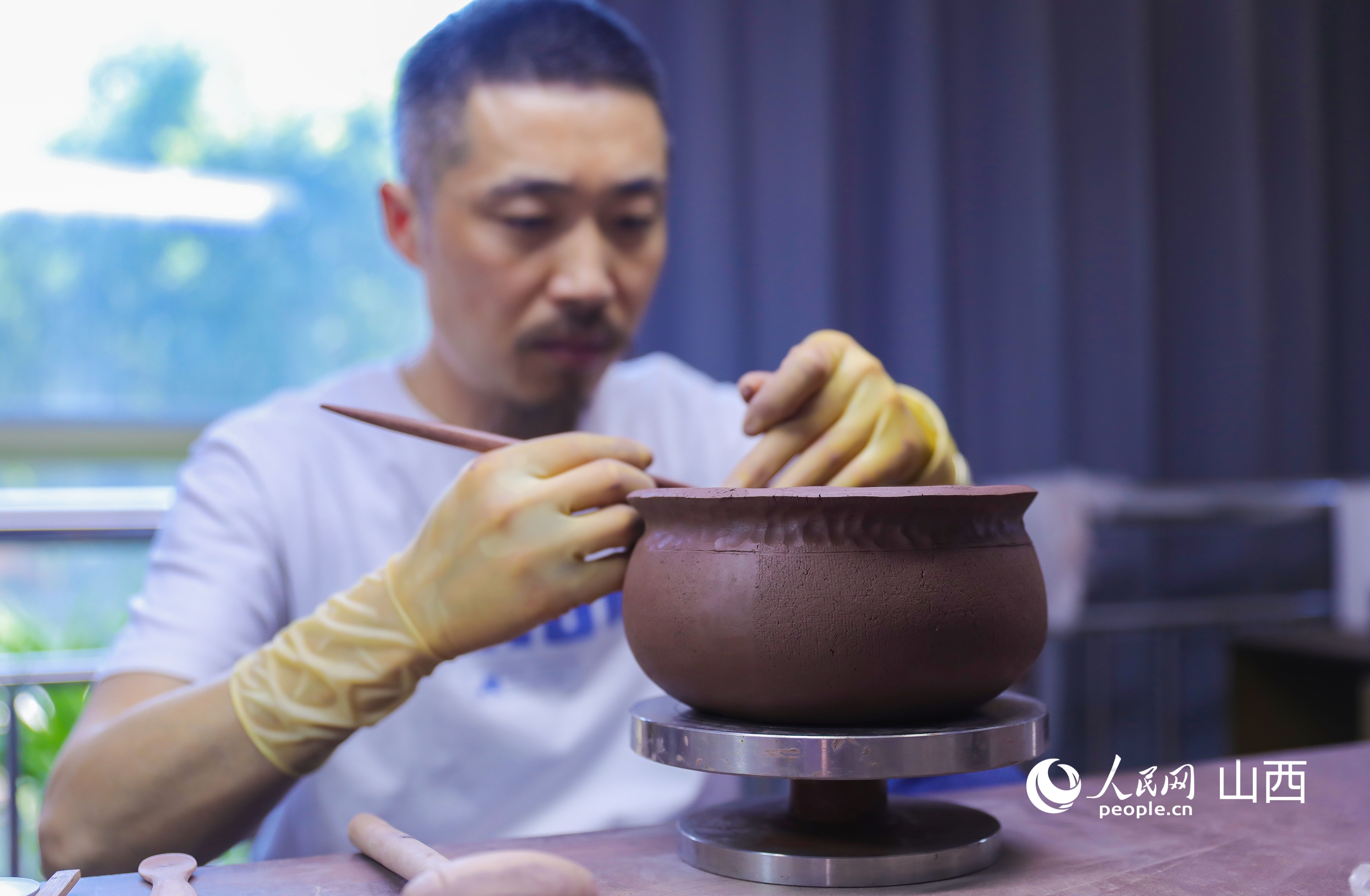 修坯属于全手工紫砂制品的核心工序，手工反复修整，能让器型线条流畅匀称。人民网记者 王帆摄